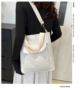 Detail view of cream-white corduroy crossbody bag with adjustable strap and front pocket