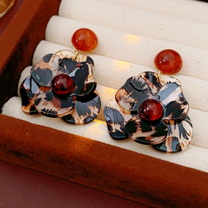 Detailed macro view of resin leopard print flower earrings in a velvet jewelry box