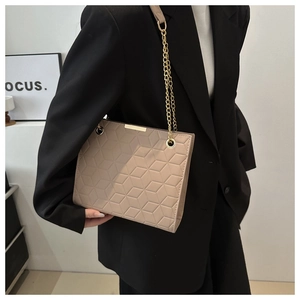 Detail of beige tote bag with 3D geometric cube embossing and gold chain strap