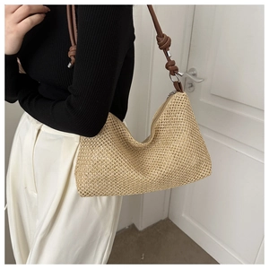 Detail of woven straw hobo bag featuring brown leather shoulder strap with knot detail