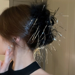 Detail of elegant black feather hair claw clip with shimmering silver fringe tassels