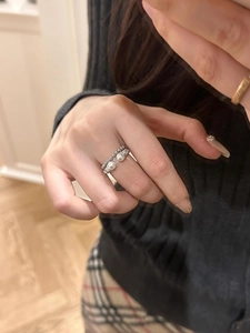 Detail of S925 silver braided pearl ring worn on model with elegant layered design
