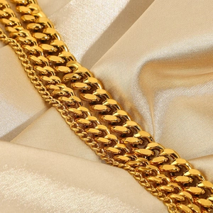 Detailed macro shot of high-polish gold Cuban link chains on luxury champagne silk fabric