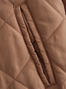 Detail of brown quilted jacket showing classic diamond stitching and slant pocket design