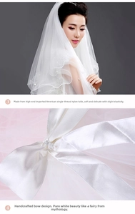 Detail of a white bridal veil with handmade bow and elegant pearl embellishments