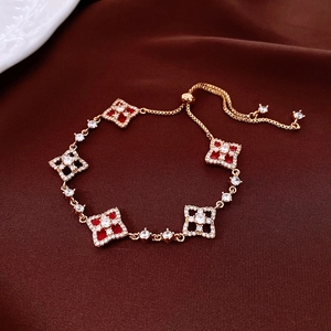 Close-up of adjustable gold-plated bracelet with red clover charms and sparkling zircons