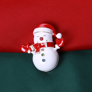 Détail de la broche bonhomme de neige en émail avec strass colorés sur tissu festif