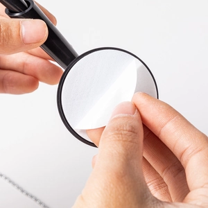 Adhesive base of a black plastic counter pen showing easy peel-and-stick installation