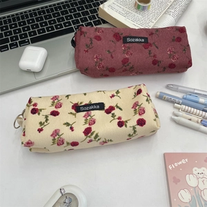 Detail of vintage floral corduroy pencil cases in dusty rose and cream colors on a desk