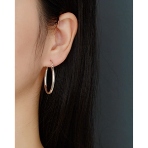 Close-up of minimalist polished 925 silver hoop earrings worn on a model's ear