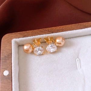 Détail de puce d'oreille papillon or 18K avec perle champagne et zircon ovale en boîte
