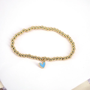 Close-up of golden beaded bracelet featuring a light blue enamel heart charm detail