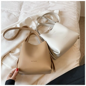 Detail view of khaki and beige leather bucket bags with handles and shoulder straps