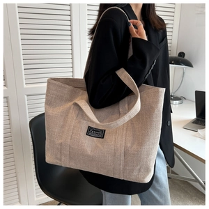 Close-up of beige canvas tote bag showing the fashion label and large capacity texture