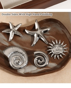 Polished silver starfish and seashell charms on a ceramic plate with detailed textures