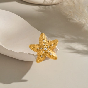 Elegant gold starfish ring with crystal texture on a decorative shell background
