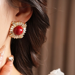 Close-up of vintage gold earrings with red round stone and crystal halo on model