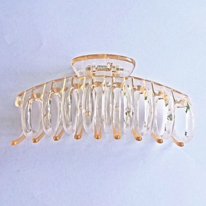 Detailed close-up of a large amber transparent plastic hair claw clip with metal spring