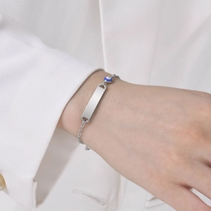 Macro shot of silver stainless steel chain bracelet with evil eye and engravable plate