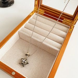 Detailed macro of a star pendant necklace with cross motif on a linen jewelry box