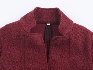 Detail of the high-quality burgundy boucle wool texture and collar craftsmanship on a coat