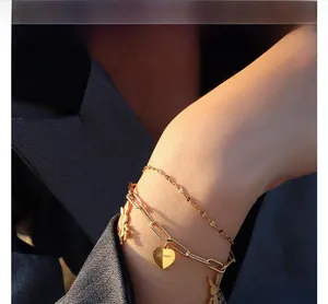 Detail view of double-layered gold bracelet with bunny charm and engraved love heart pendant