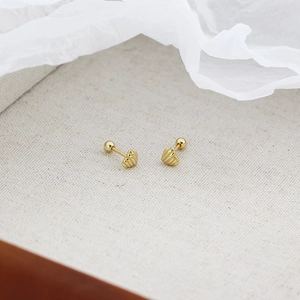 Macro shot of gold heart-shaped stud earrings with screw back on a neutral linen backdrop
