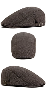 Detail of brown herringbone flat cap featuring adjustable metal side buckle and wool texture