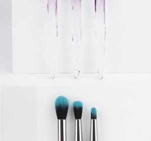 Macro shot of gradient purple crystal handles and two-tone synthetic bristle makeup brushes