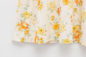 Detail eines Blumenmusters mit gelben und orangen Rosen auf cremefarbenem Stoff