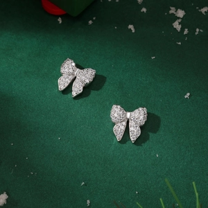 Close-up of silver butterfly earrings with white zircon on dark green winter background
