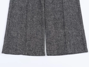 Detail view of the herringbone pattern and hem stitching on dark grey trouser cuffs