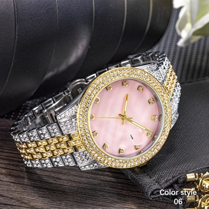 Detailed close-up of a pink dial luxury watch with gold markers and crystal-set gold bezel