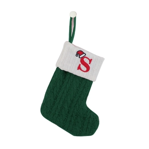 Detail of green knitted Christmas stocking with a red embroidered letter S and white cuff