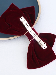 Macro detail of the metal spring clip on a deep red velvet bow hair accessory