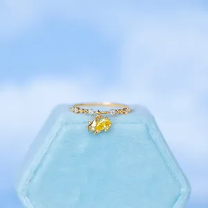 Detail of 18K gold ring with three white zircons and a cute yellow dinosaur pendant
