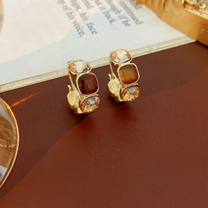 Macro detail of vintage gold U-shaped earrings with amber crystal stones on book pages
