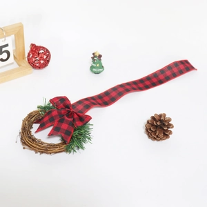 Detail of Christmas wreath with buffalo plaid bow and greenery on a white background