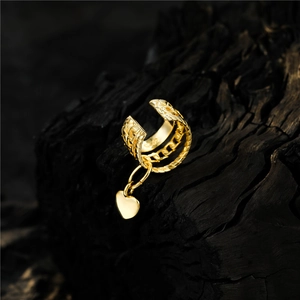 Elegant gold heart ear cuff with woven chain texture on a charcoal wooden background