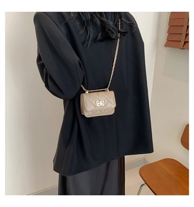 Quilted mini crossbody bag in khaki with gold chain strap shown on a black blazer