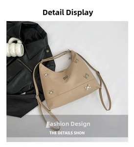 Detail view of beige crossbody bag with silver butterfly accents and zipper closure
