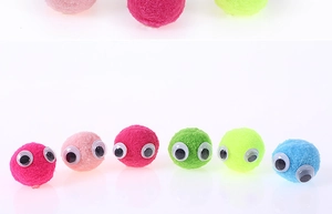 Close-up of colorful plush balls with plastic eyes for DIY craft making and decoration