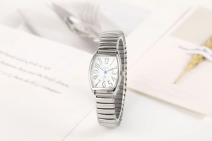 Détail d'une montre tonneau argentée avec bracelet extensible sur fond minimaliste