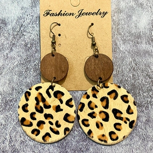 Detail of western earrings featuring leopard print leather and dark wood round charms
