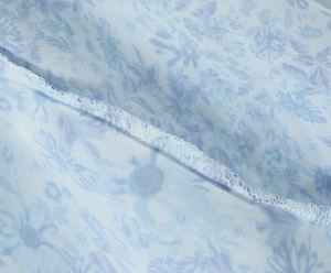 Detailed close-up of light blue floral dress seam with high-quality overlock stitching