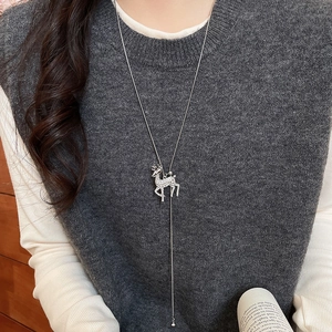 Silver reindeer pendant necklace with sparkling rhinestones worn on a grey knit sweater