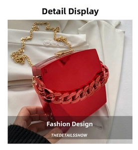 Detail shot of a glossy red square hard shell handbag with red and gold chain straps