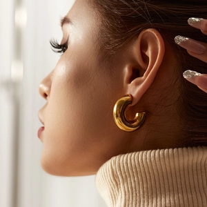 Elegant gold-tone chunky C-shaped hoop earrings for women worn by a model in a side view