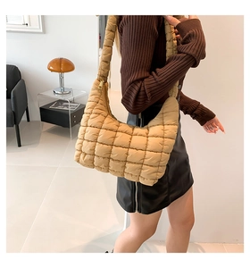 Detail of khaki quilted puffer shoulder bag with soft square padded texture and wide strap