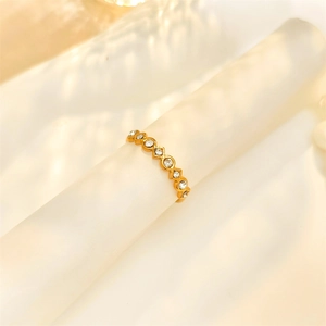 Detailed view of wave-shaped gold ring with white zircons on frosted display